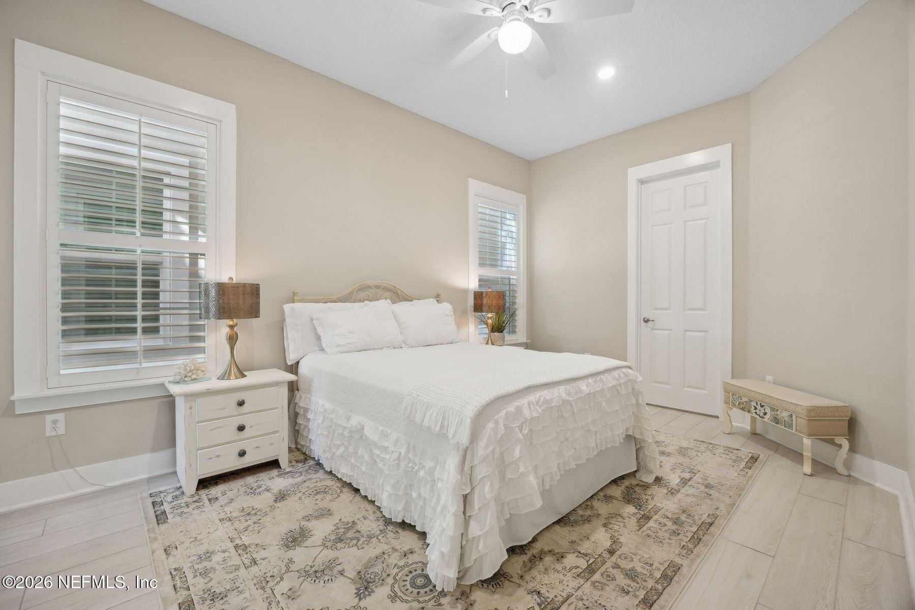 Primary bedroom with wood floors and plantation shutters